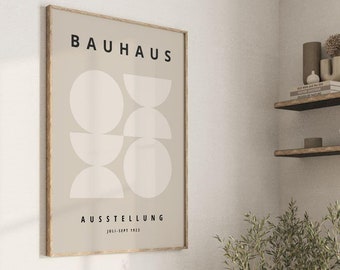 May include: A beige poster with a black frame featuring a geometric design of white circles and semi-circles. The text "BAUHAUS" and "AUSSTELLUNG JULI-SEPT 1923" is printed in black.