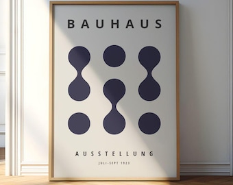 May include: A framed Bauhaus exhibition poster. The poster displays the word "BAUHAUS" at the top, with dark blue shapes. Below, the word "AUSSTELLUNG" is shown, followed by "JULI-SEPT 1923". The frame is a light brown colour.