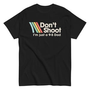 May include: Black crew neck t-shirt featuring the text "Don't Shoot I'm just a 9-5 Dad" in white, with a retro design of blue, green, yellow, and red stripes. The shirt is made of a soft material.