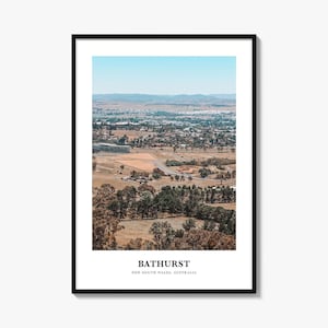 May include: A framed wall art print featuring a high-angle landscape photograph of Bathurst, New South Wales, Australia. The image displays a sprawling town with dry, golden-brown fields, green trees, and distant hills under a clear blue sky. The text BATHURST NEW SOUTH WALES, AUSTRALIA is printed in black at the bottom.