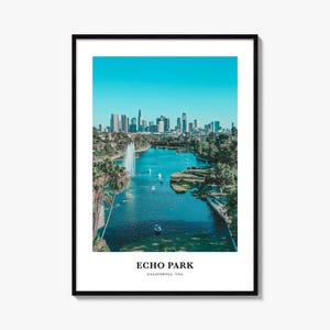 May include: A framed wall art print featuring a scenic view of Echo Park Lake in Los Angeles, California. The image displays a blue lake with a fountain, palm trees, and the city skyline in the background. The text reads ECHO PARK CALIFORNIA, USA.