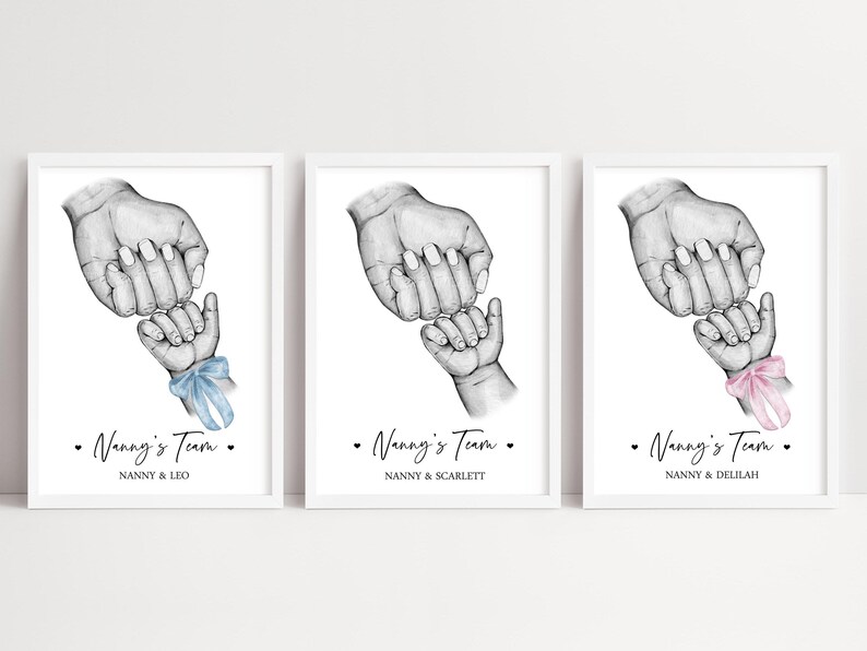 May include: Three framed prints featuring a black and white pencil sketch of an adult hand holding a baby hand. Each print includes the text Nanny's Team and a name, with one baby hand wearing a blue ribbon and another wearing a pink ribbon.