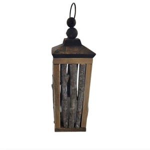 May include: A rustic wooden lantern with a dark brown top and a light brown frame. The lantern features vertical wooden sticks inside the frame and a black metal loop for hanging. A decorative item for home decor.
