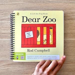 May include: A yellow lift-the-flap book titled "Dear Zoo" with a red and white cage with a lion inside. The book is interactive and adapted for learners with specific needs. It includes interactive panels and picture word supported text.
