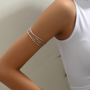 May include: A silver arm cuff with a twisted design. The cuff is worn on the upper arm.
