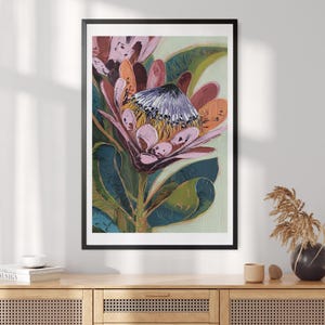 Puede incluir: Impresión artística enmarcada de una flor de protea en tonos rosa, naranja y morado. La flor presenta pétalos texturizados y un centro con pequeñas flores claras. El fondo es de un verde suave, creando un contraste delicado.