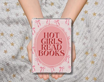 May include: A pink tablet case with the text "HOT GIRLS READ BOOKS" in a decorative oval. The case has a light pink background with a pattern of bows and ribbons. The tablet is held in front of a gray and white star-patterned background.