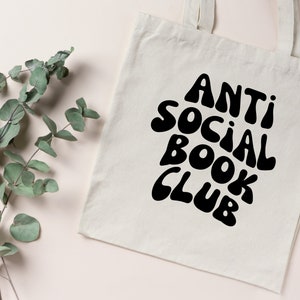 May include: White tote bag with black text that reads "Anti Social Book Club" in a retro font.