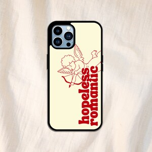 Puede incluir: Una funda de tel&eacute;fono blanca con un contorno rojo de un cupido con una flecha y el texto "hopeless romantic".