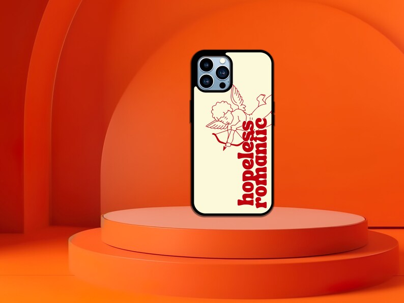 Puede incluir: Una funda blanca para iPhone con un gr&aacute;fico rojo y blanco de un cupido con una flecha y el texto "hopeless romantic".