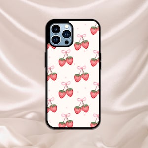 K&ouml;nnte beinhalten: Eine wei&szlig;e Handyh&uuml;lle mit einem Muster aus pinkfarbenen, roten Erdbeeren. Die H&uuml;lle hat einen schwarzen Rand und einen Ausschnitt f&uuml;r das Kameraobjektiv.