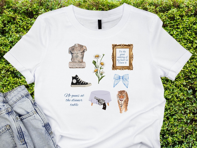 May include: White t-shirt with a variety of graphics, including a statue, a pair of sneakers, a bouquet of daisies, a bow, a table setting, a gun, a tiger, and a framed quote that reads "It's the great undoing of my heart as I know it".