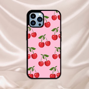 Puede incluir: Una funda de teléfono rosa con un patrón repetido de cerezas rojas. La funda tiene un borde negro y un recorte para la cámara.
