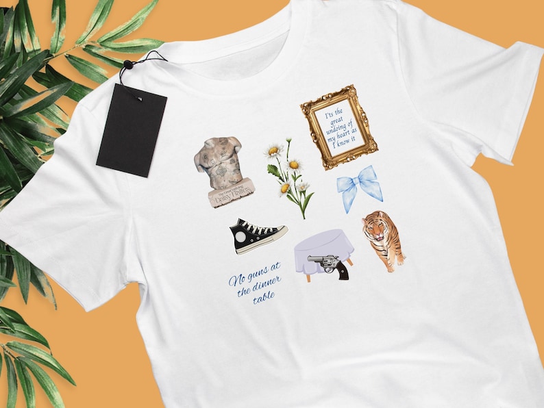 May include: White t-shirt with various illustrations printed on it. The illustrations include a bust sculpture, a pair of sneakers, a daisy, a blue bow, a tiger, a table with a gun on it, and a quote that reads "It's the great undoing of my heart as I know it". The text "No guns at the dinner table" is also printed on the shirt.