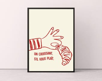 May include: A framed wall art print featuring a red line drawing of a hand reaching for a croissant on a cream background. The text "UN CROISSANT, S'IL VOUS PLAÎT." is printed in red below the hand. The artwork is enclosed in a thin black frame.