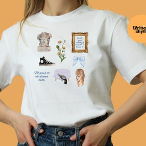 May include: White t-shirt with a variety of colorful illustrations, including a statue, flowers, a gun, a tiger, a table, a pair of shoes, and a bow. The text on the shirt reads "I'm the great undoing of my heart as I know it" and "No guns at the dinner table."