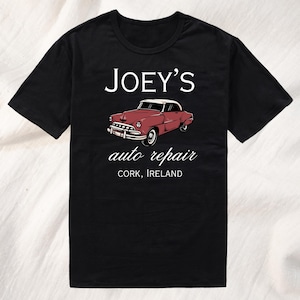 May include: Black t-shirt with white text that reads "JOEY'S auto repair CORK, IRELAND". A vintage red car is pictured above the text.