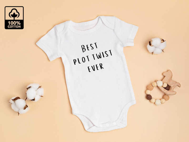 May include: White baby onesie with short sleeves and the text "Best Plot Twist Ever" printed in black.