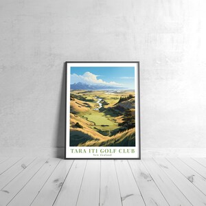 May include: A framed poster with a scenic view of a golf course in New Zealand. The poster features a green golf course with a river running through it, surrounded by rolling hills and a blue sky with white clouds. The text "Tara Iti Golf Club" and "New Zealand" is printed at the bottom of the poster.