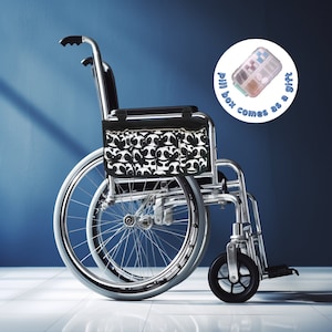 Peut inclure: Un sac à motifs noir et blanc est attaché à un fauteuil roulant argenté. Le fauteuil roulant a deux grandes roues et deux petites roues. Le texte sur le cercle blanc dit "Pill box comes as a gift."