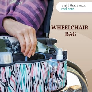 Op de afbeelding: Een rolstoeltas met een abstract, meerkleurig zebramotief in teal, roze en zwart. De tas heeft meerdere buitenvakken met daarin een doorzichtig pillendoosje, een witte sprayflacon en een bril. Tekst: a gift that shows real care, WHEELCHAIR BAG.