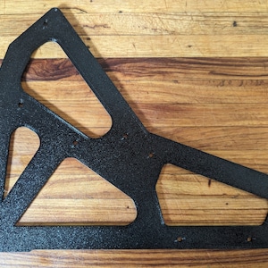May include: Black metal bracket with a geometric design. The bracket has several cutouts and is textured with a fine black finish.