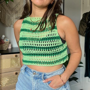 Puede incluir: Un top corto de crochet verde y verde claro con un patrón de rayas. El top es sin mangas y tiene un escote redondo.