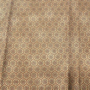 May include: Close-up of a fabric with a repeating pattern of small, dark red and black dots arranged in a hexagonal design on a tan background. The fabric has a slightly wrinkled texture.
