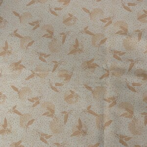 May include: Cream-colored fabric with a repeating pattern of light brown leaves and dotted accents. The leaves are stylized and arranged in a scattered design across the surface of the fabric. The overall effect is soft and natural.