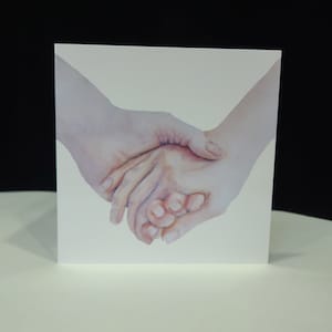 Een foto van een stel dat elkaars hand vasthoudt, gedrukt op een wenskaart.