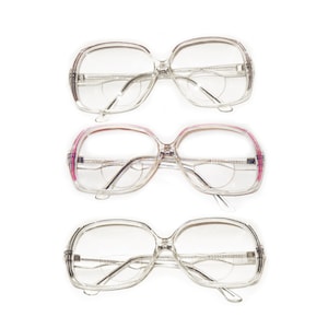 Könnte beinhalten: Drei Paar Brillen mit klarem Kunststoffgestell und verschiedenen Farbakzenten. Das obere Paar hat klare Akzente, das mittlere Paar hat rosa Akzente und das untere Paar hat schwarze Akzente.
