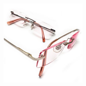 May include: A pair of rimless glasses with a silver frame and pink accents. The glasses are shown from two different angles.