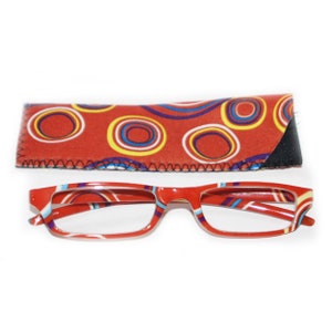 Puede incluir: Gafas de lectura rojas con un estuche a juego. Las gafas y el estuche presentan un colorido patrón de círculos y rayas. Las gafas tienen una montura rectangular. El estuche es rectangular y tiene un borde cosido negro.