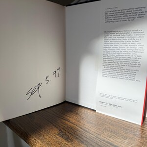 May include: An open book with text and a handwritten date, "Sep. 5.99," on the left page. The right page features text about the sun and Madanjeet Singh. The book is on a wooden surface.