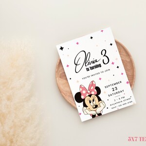 May include: A printable 5x7 inch invitation template featuring a cartoon image of Minnie Mouse with pink and black polka dots. The text on the invitation reads "Olivia is turning 3. You're invited to join. September 23, Saturday, 2-6 PM, Anywhere street, RSVP: 125-436-4789".