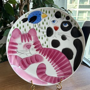 Assiette murale en céramique Helina Tilk grand format (31 cm) « Chat et oiseau », peinte à la main, céramique d'atelier estonienne, décoration féline fantaisiste, cadeau pour les amoureux des chats.