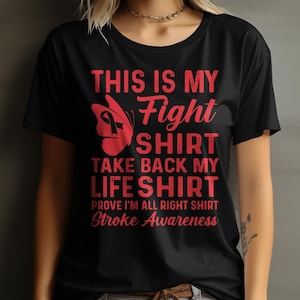 May include: Black t-shirt with red text that reads "This is my Fight Shirt Take Back My Life Shirt Prove I'm All Right Shirt Stroke Awareness". A red butterfly with a red ribbon is above the text.