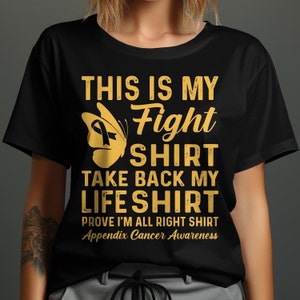 May include: Black t-shirt with gold text that reads "This is my Fight Shirt Take Back My Life Shirt Prove I'm All Right Shirt Appendix Cancer Awareness". A gold butterfly with a yellow ribbon is above the text.