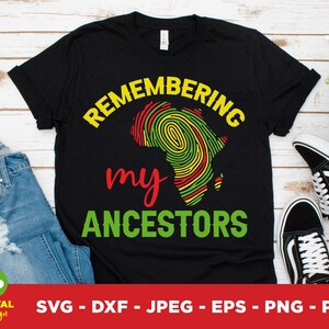 May include: Black t-shirt with the words "REMEMBERING my ANCESTORS" in yellow, red, and green. The design includes a fingerprint-style map of Africa. The shirt is displayed with blue jeans and black and white sneakers.