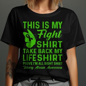 Op de afbeelding: Zwart T-shirt met groene tekst die luidt "This is my Fight Shirt Take Back My Life Shirt Prove I'm All Right Shirt Biliary Atresia Awareness". Een groene vlinder met een groen lint bevindt zich boven de tekst.