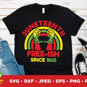 Peut inclure: T-shirt noir avec un graphisme coloré célébrant le Juneteenth. Le design comprend le texte "JUNETEENTH FREE-ISH SINCE 1865" avec un poing et des éléments arc-en-ciel. Le t-shirt est présenté avec un jean et des baskets.
