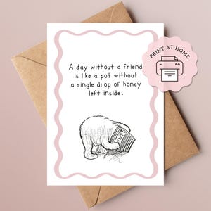 Puede incluir: Una tarjeta de felicitación blanca con un borde rosa y un sobre marrón. La tarjeta presenta una ilustración en blanco y negro de un oso y el texto: "Un día sin un amigo es como una olla sin una sola gota de miel dentro."