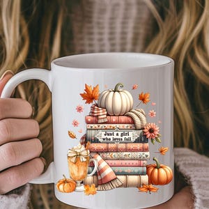 May include: White ceramic mug featuring a fall-themed design. The design includes a stack of books, a pumpkin, fall leaves, and a latte. The text on the mug reads "Just a girl who loves fall."