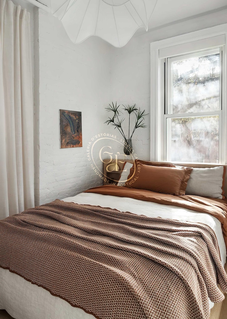 Manta portuguesa castanha estendida numa cama de casal, destacando o seu tamanho generoso. Portuguese brown blanket spread on a double bed, showing its generous size.