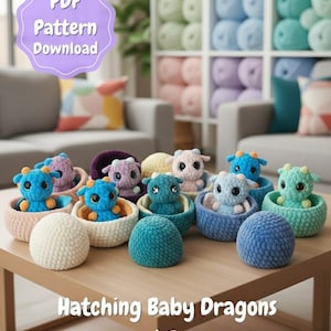 May include: A display of colourful crocheted baby dragons, each in a basket, with matching crocheted eggs. The image features the text "Hatching Baby Dragons and Eggs". A purple sign says "PDF Pattern Download".