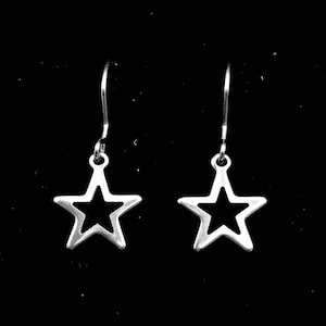 May include: A pair of silver star-shaped earrings with a simple, open design. The earrings are suspended from a thin silver wire.