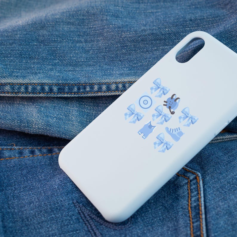 May include: A white phone case with a blue and white design featuring bows, a cat, a shoe, and a circle. The case is on a blue denim background.