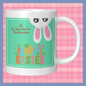 May include: White ceramic mug with a green background and a bunny peeking over the top. The text "Hi, I'm just here for the chocolate" is on the mug. The words "Happy Easter" are in colorful letters on the mug.