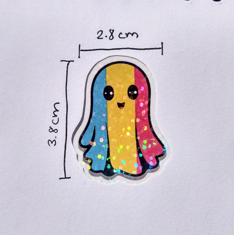 May include: A glittery ghost-shaped sticker, 3.8 cm tall and 2.8 cm wide, displaying the pansexual pride flag colours: blue, yellow, and pink. The ghost has a smiling face with black eyes and a black mouth. The sticker has a holographic effect.