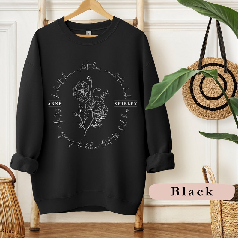 May include: Black sweatshirt with a white floral design and the text "I don't know what lies around the bend but I'm going to believe that the best days" with the names "Anne Shirley" on either side of the floral design.